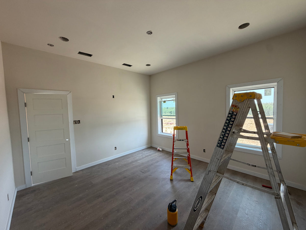 Finished bedroom with painted walls, luxury vinyl plank flooring, and a white five-panel door during final trim-out