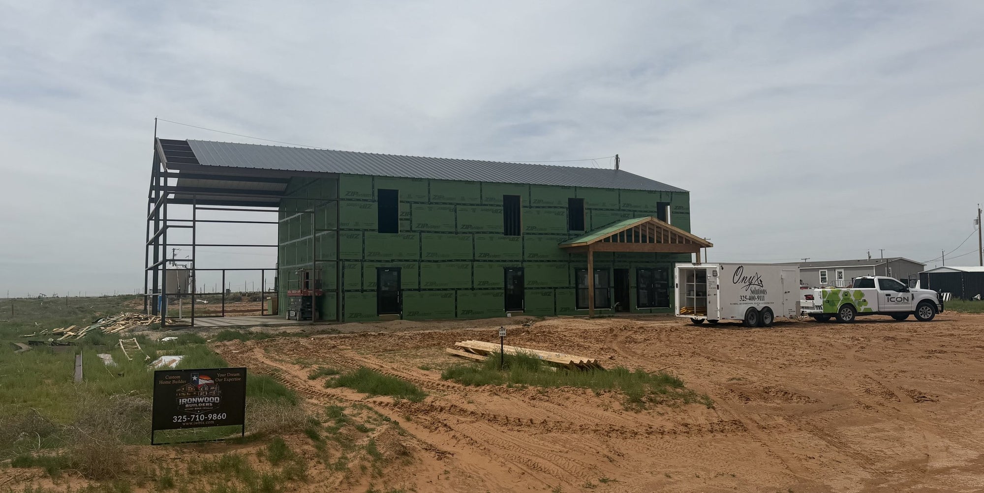 Ironwood Builders job site sign in front of a two-story custom home under construction with company trucks and trailer parked on site